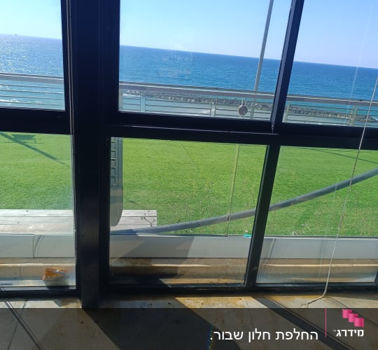 חלון גדול עם נוף לים ודשא ירוק
